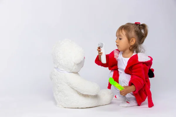 Lindo niño jugando con su oso de peluche enfermo. Juego de rol, niña jugando al doctor con peluche. Niños y gripe, concepto de enfermedad por coronavirus. — Foto de Stock