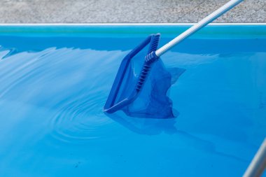 Mavi havuzu temizlemek için bir süzgeç ağı kullanılıyor. Suyu temiz ve davetkar tutuyor.