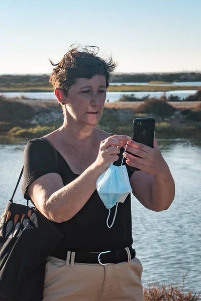 Yaşlı kadın tatilde antivirüs maskesi takarak selfie çekiyor..