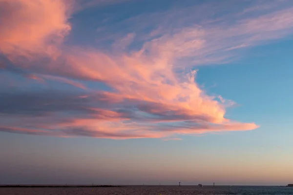 Alacakaranlıkta kırmızı bulutlar fotoğrafın sonunda suyla birleşen kumsallardır.-