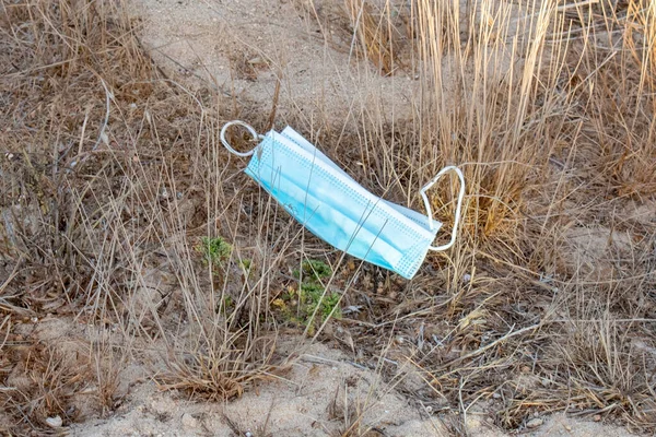 Mavi antivirüs maskesi kuru otların etrafındaki sokağa atılmış ve kirliliğe yol açmış.