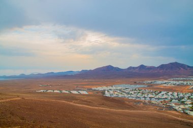 Volkan Montana Roja de Playa Blanca 'nın panoramik manzarası, Lanzarote, İspanya. Kanarya Adaları 'ndaki en popüler volkanlardan biri ve güneydeki beyaz evlerin toplam manzarası.. 
