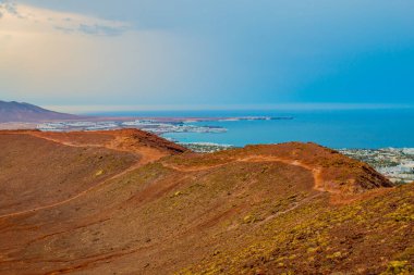 Volkan Montana Roja de Playa Blanca 'nın panoramik manzarası, Lanzarote, İspanya. Kanarya Adaları 'ndaki en popüler volkanlardan biri ve güneydeki beyaz evlerin toplam manzarası.. 
