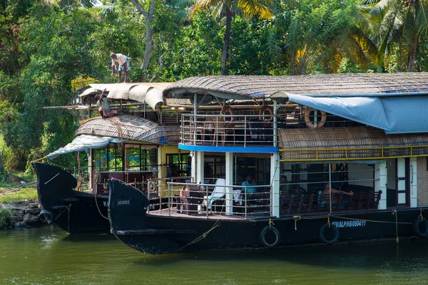 Güneşli bir günde Kerala 'nın durgun suyunun yanındaki küçük bir köyde küçük evler ve Allapuzza veya Alleppey' in pitoresk durgun sularında yüzen geleneksel yüzen yüzen yüzen yüzen tekneler görülüyor.