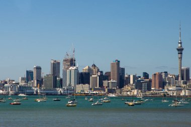 İnsanlar günlük yaşamlarını Auckland şehir merkezinde (Yeni Zelanda), bir yaz günü okyanusun yanında, ana caddelerde geçirirler. Şehir dükkanlar ve gökdelenlerle dolu. Modern bir şehir manzarası.. 