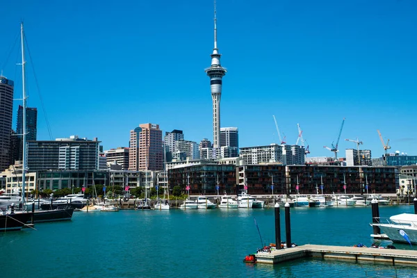 İnsanlar günlük yaşamlarını Auckland şehir merkezinde (Yeni Zelanda), bir yaz günü okyanusun yanında, ana caddelerde geçirirler. Şehir dükkanlar ve gökdelenlerle dolu. Modern bir şehir manzarası.. 