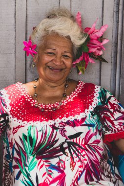 Portrait of an old woman smiling in Papeete, French Polynesia. A vendor dressing traditional tropical flowers.  clipart