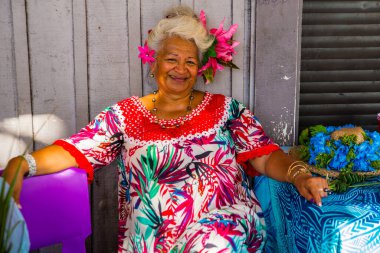 Portrait of an old woman smiling in Papeete, French Polynesia. A vendor dressing traditional tropical flowers.  clipart