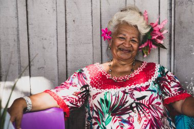 Papeete, Fransız Polinezyası 'nda gülümseyen yaşlı bir kadının portresi. Geleneksel tropik çiçekleri giydiren bir satıcı.. 