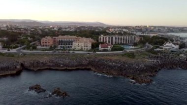 Portekiz 'in Lizbon kentindeki Cascais köyünün gün batımında inanılmaz hava manzarası. Okyanusa yakın bir şehrin manzarası. Denizin panoramik manzarası ve TheBoca do Inferno gibi diğer doğal manzaralar için gelenler..