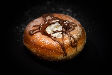 İtalyan kahvaltısında izole edilmiş taze çörek, içinde şeker ve el yapımı krem şanti ve siyah arka planda lezzetli çikolata.