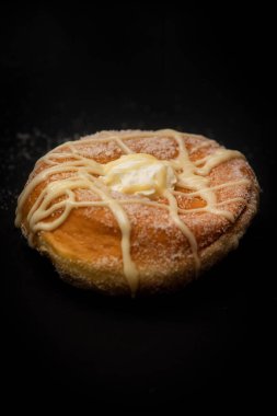 İtalyan kahvaltısında izole edilmiş taze çörek, içinde şeker ve el yapımı krem şanti ve siyah arka planda lezzetli çikolata.