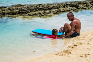 Moorea, Fransız Polinezyası: 09 / 03 / 2018: Bir baba ve kızı, tropikal Moorea adasında bir yaz gününde beyaz plajda ve mavi okyanusta eğleniyor.