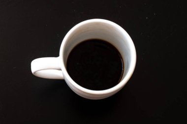 Siyah arka planda beyaz bardakta taze İtalyan kahvesi.