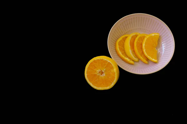 新鲜橙子做早餐 背景是黑色的 水果在粉红色的盘子里分成小片 — 图库照片