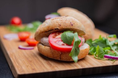 Sığır eti, soğan, domates, marul ve peynirli ev yapımı hamburger. Tahta kırsal masada taze sebzeli taze burger. Çizburger.