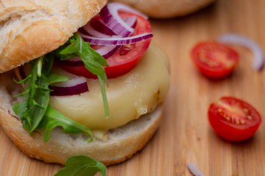 Sığır eti, soğan, domates, marul ve peynirli ev yapımı hamburger. Tahta kırsal masada taze sebzeli taze burger. Çizburger.