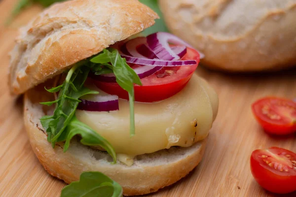 Sığır eti, soğan, domates, marul ve peynirli ev yapımı hamburger. Tahta kırsal masada taze sebzeli taze burger. Çizburger.