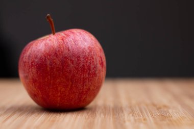 Ahşap bir arka planda taze bir kırmızı elma. Taze ve sağlıklı kahvaltı meyvesi.