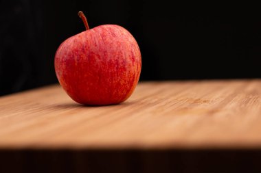 Ahşap bir arka planda taze bir kırmızı elma. Taze ve sağlıklı kahvaltı meyvesi.