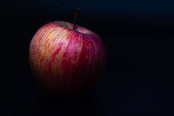 One red fresh apple on a black background. Healthy fruit and breakfast