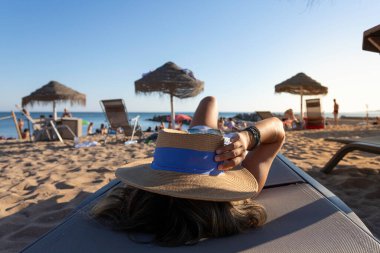 Güzel Vietnamlı kadın Portekiz, Lizbon 'da Atlantik Okyanusu' na bakan plaj yatağında dinleniyor. Beyaz bir elbise giyen şık bir kızın arka görüntüsü. Özgürlük tatilindeki kız.