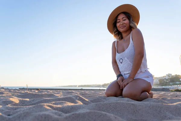 Beautiful Vietnamese woman alone playing and relaxing on the beach. Asian woman on holiday in a luxury resort in Portugal traveling alone around the world. Woman's lifestyle concept of freedom