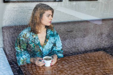 Kafede oturan ve kahvenin tadını çıkaran genç bir kadının portresi. Kahve barı Lizbon, Portekiz tren istasyonunun yanında. Ahşap masaları ve taze lezzetli yemekleri olan bir yer.