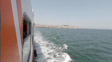 Portekiz 'de Lizbon' un merkezindeki Tagus Nehri 'nden geçen küçük bir turistik feribotun hava görüntüsü. Gün batımında Atlantik Okyanusu 'nda yüzen küçük bir geminin güzel hava manzarası. Arka planda mavi bir gökyüzü var.