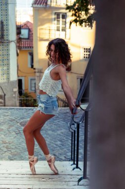 Lizbon, Portekiz 'deki şehir manzarasında poz veren genç bir balerin. Çekici genç kadın Portekiz sokaklarında çağdaş bale yapıyor. Kadın yaşam tarzı konsepti