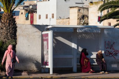 Casablanca, Fas: 09 / 07 / 2019: İnsanlar bir yaz günü Kazablanka şehir merkezindeki otobüs durağında konuşuyor ve bekliyor. Burası ıssız ve eski binalarla dolu. İnsanlar rahatlar.