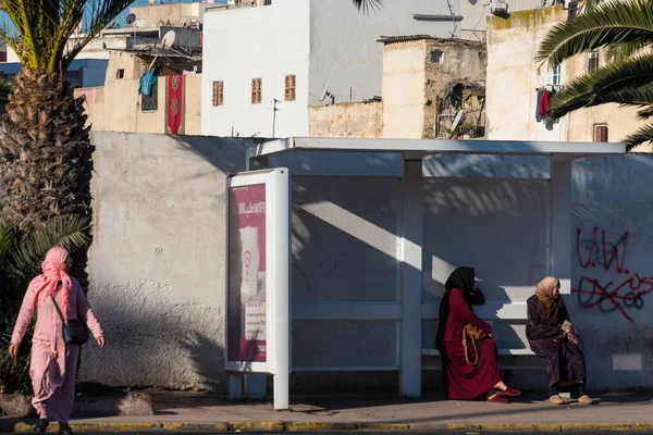 Casablanca, Fas: 09 / 07 / 2019: İnsanlar bir yaz günü Kazablanka şehir merkezindeki otobüs durağında konuşuyor ve bekliyor. Burası ıssız ve eski binalarla dolu. İnsanlar rahatlar.