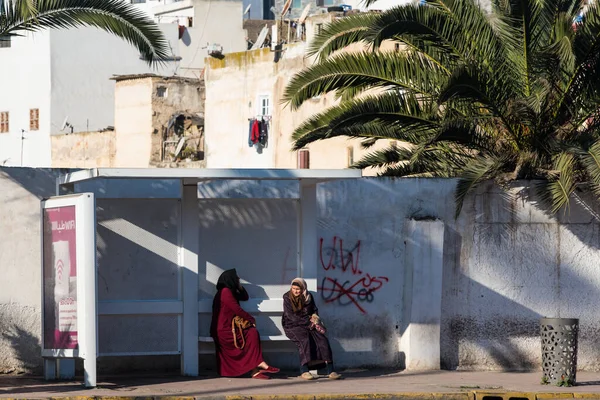 Casablanca, Fas: 09 / 07 / 2019: İnsanlar bir yaz günü Kazablanka şehir merkezindeki otobüs durağında konuşuyor ve bekliyor. Burası ıssız ve eski binalarla dolu. İnsanlar rahatlar.