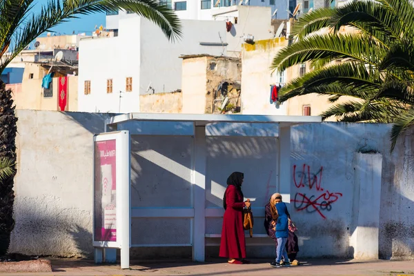 Casablanca, Fas: 09 / 07 / 2019: İnsanlar bir yaz günü Kazablanka şehir merkezindeki otobüs durağında konuşuyor ve bekliyor. Burası ıssız ve eski binalarla dolu. İnsanlar rahatlar.