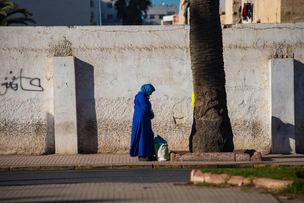 Casablanca, Morocco: 09/07/2019 : Portrait of a muslim woman with her head covered walking in the city center of Casablanca in a sunny day. Woman crossing the streets of the eastern markets