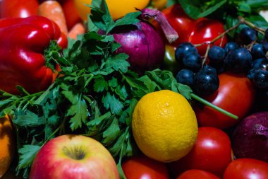 Sebzelerin arka planı farklı taze çiftlik sebzeleri. Yiyecek ya da Sağlıklı Diyet Konsepti, Üst Manzara ve Işık Efektleri. Çeşitli organik sebzelerle kompozisyon. Detoks diyeti: limon, domates, biber, karnabahar, elma, üzüm