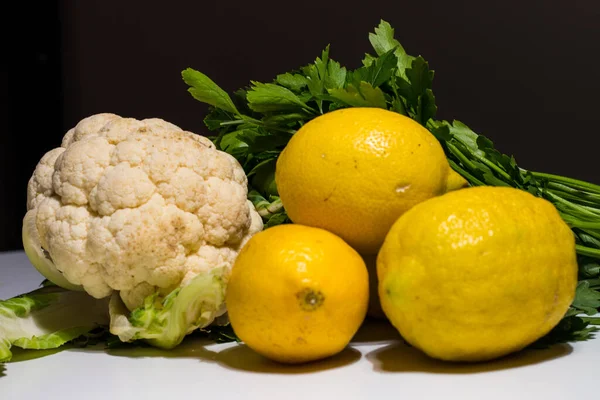 composition of lemons and cauliflower on white background. Yellow lemons and white raw whole cauliflower. Fresh and healthy vegetables. Italian food. vegetarian healthy food concept.