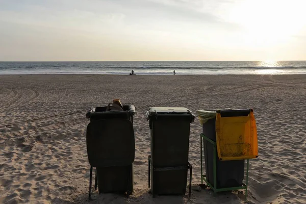 Isolated trash bins on the beach facing the Atlantic Ocean in Costa da Caparica in Lisbon. Environment concept lifestyle of waste management and recycling policy. Portugal, 2020