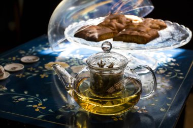 Bir fincan taze çiçek, bitki çayı ve biraz lezzetli ve sağlıklı badem kurabiyesi, vitamin açısından zengin ve az şekerli. Boşluğu kopyala. Mavi çiçekli arkaplanda üst görünüm.