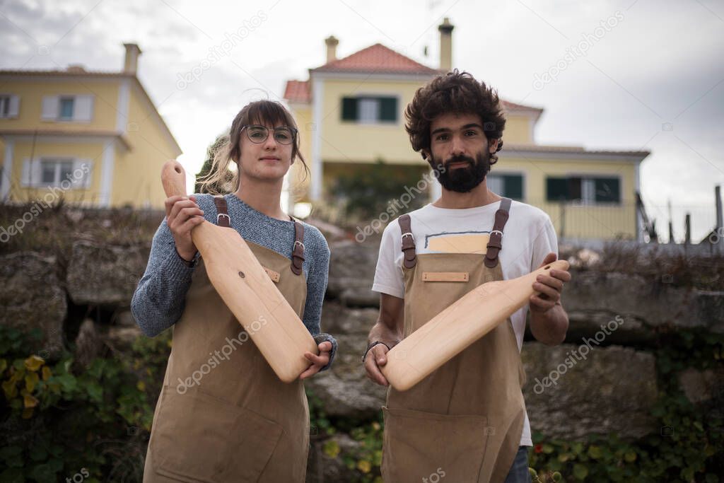 A young couple of carpenters working together in a small carpentry workshop designing a new home furniture piece crafting out of timber. Young entrepreneurs running their own business in Lisbon