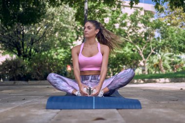 Spor salonundaki kadın dışarıda paspas üzerinde egzersiz yapıyor.