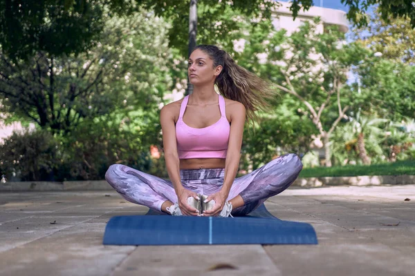 Spor salonundaki kadın dışarıda paspas üzerinde egzersiz yapıyor.