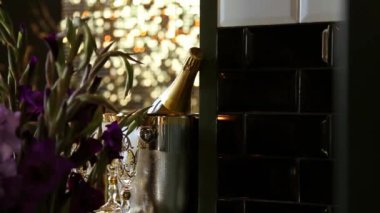 Gümüş kovada bir şişe altın şampanya ve bir buket leylak gladioli.