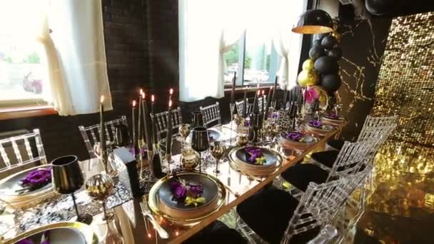 スローモーションゴールドゴールドカトラリーブラックワイングラスブラックキャンドルゴールドとゴールドスタイルでパーティーの装飾のための休日のテーブルの黒風船 — ストック動画