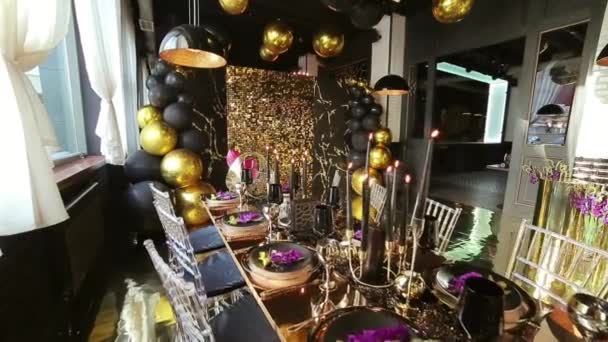 缓慢运动的黄金餐具黑色酒杯黑色蜡烛金色和黑色气球在节日桌上装饰金色风格的派对 — 图库视频影像