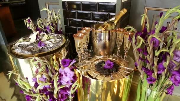 皿の上のスプーンに黒のキャビア黄金のワイングラス銀バケツのシャンパンボトルライラックグラジオリパーティーの装飾のための黄金のスタイル — ストック動画