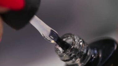 Profesyonel manikür. Çivi uzantısı. İnce bir fırçanın yakın plan çekimleri bir baloncuktan Lehçe kazanıyor.