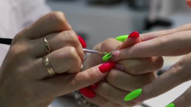 Profesyonel manikür. Çivi uzantısı. Tırnak tabanına vernikle kaplanmış sanatsal bir model uyguluyorum. Modern bir güzellik salonunda jöle tırnakları yapma prosedürü.