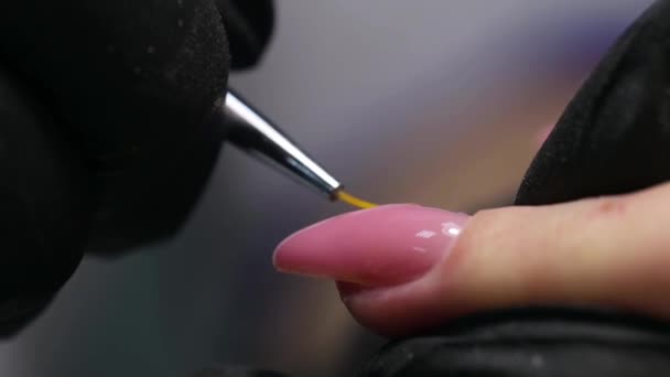 プロのマニキュア 爪の延長 ピンクの爪をブラシで1つの爪にポーランド語を適用します 現代的な美容室で長い人工ゲル爪を作るための手順 — ストック動画