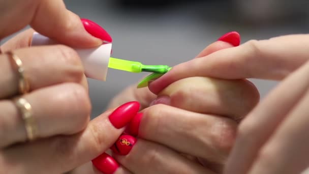 专业的修指甲 指甲的伸展 在准备好的指甲油底上涂上一层浅绿色的指甲油 — 图库视频影像
